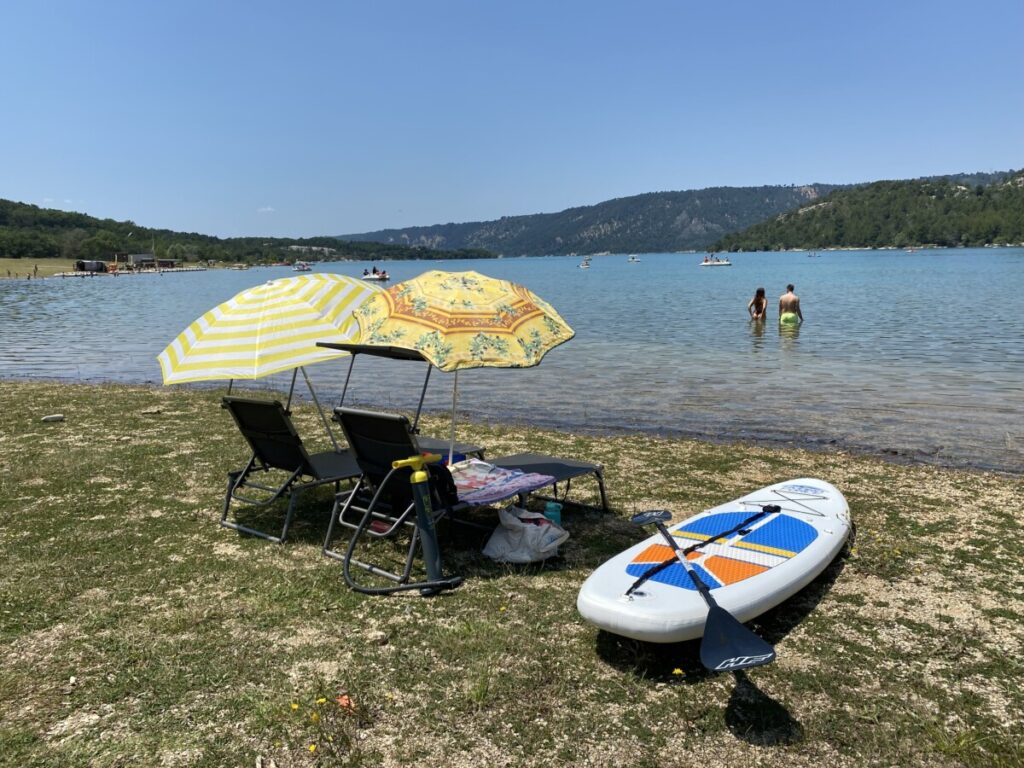 A few beach chairs, umbrellas and a paddleboard on the banks of the Gorges du Verdon and Lac de Sainte Croix in France