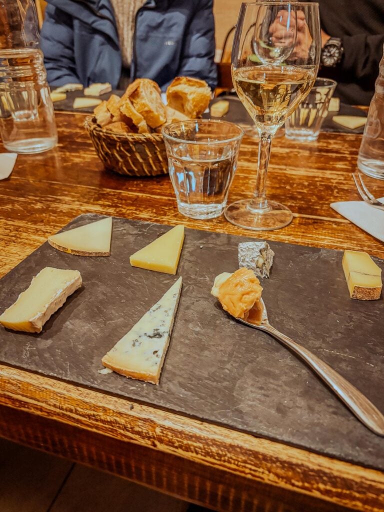 Parisian wine and cheese tasting with various French cheeses and white wine.